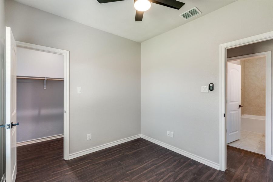 Unfurnished bedroom featuring dark wood-style floors, a spacious closet, and a ceiling fan Unfurnished bedroom featuring dark wood-style floors, a spacious closet, and a ceiling fan