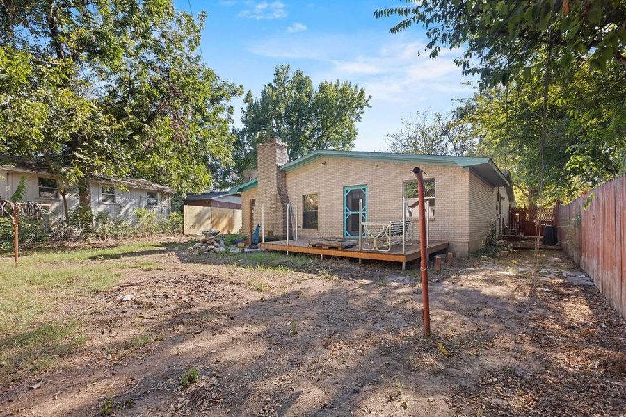 Back of property featuring a chimney, a wooden deck, and brick siding