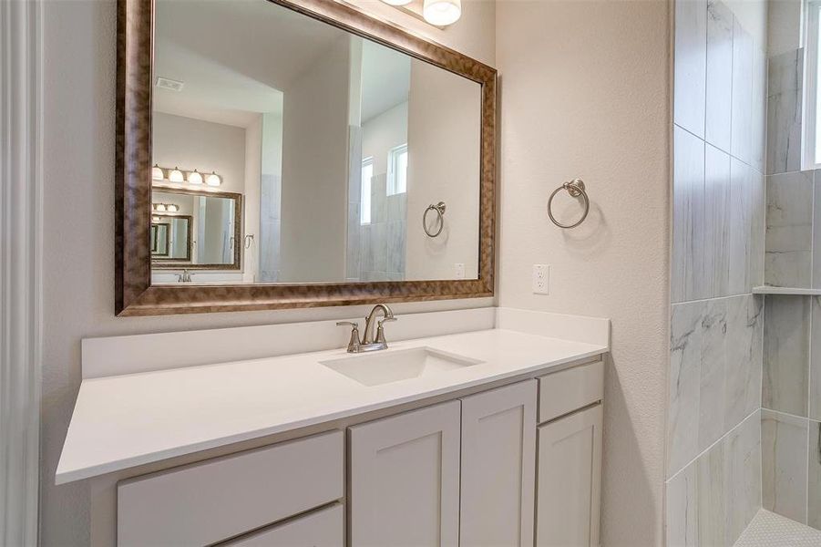 Bathroom with vanity and tiled shower