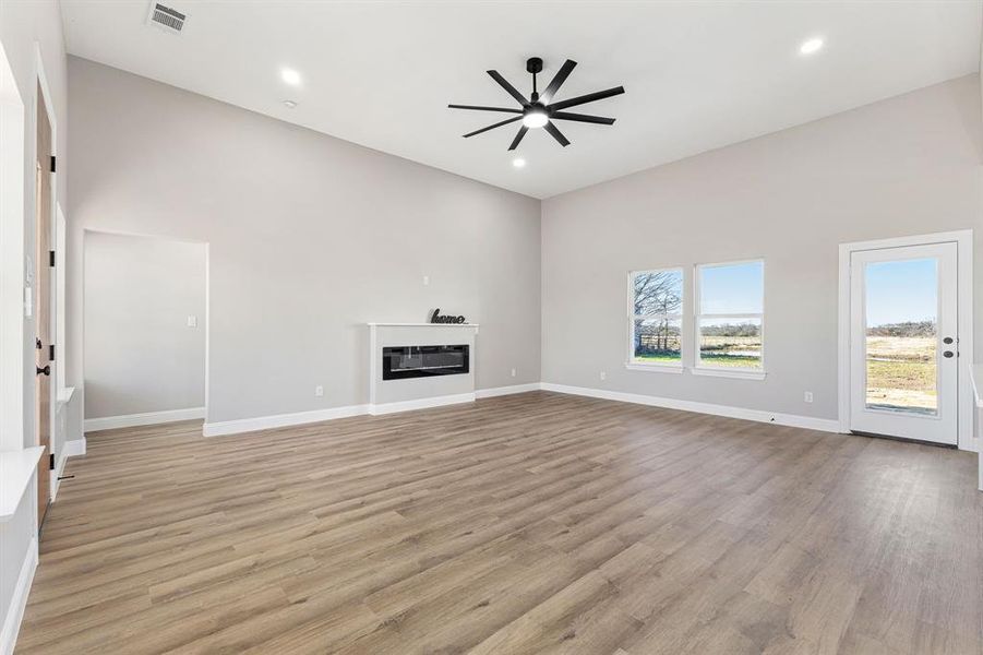 Unfurnished living room featuring light hardwood / wood-style floors, high vaulted ceiling, and ceiling fan