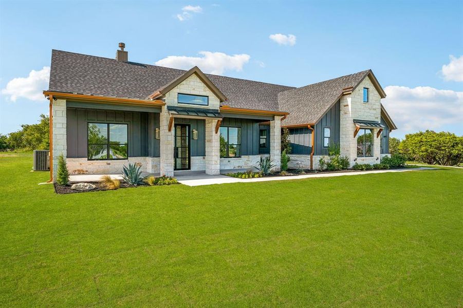 View of front of house with central air condition unit and a front yard