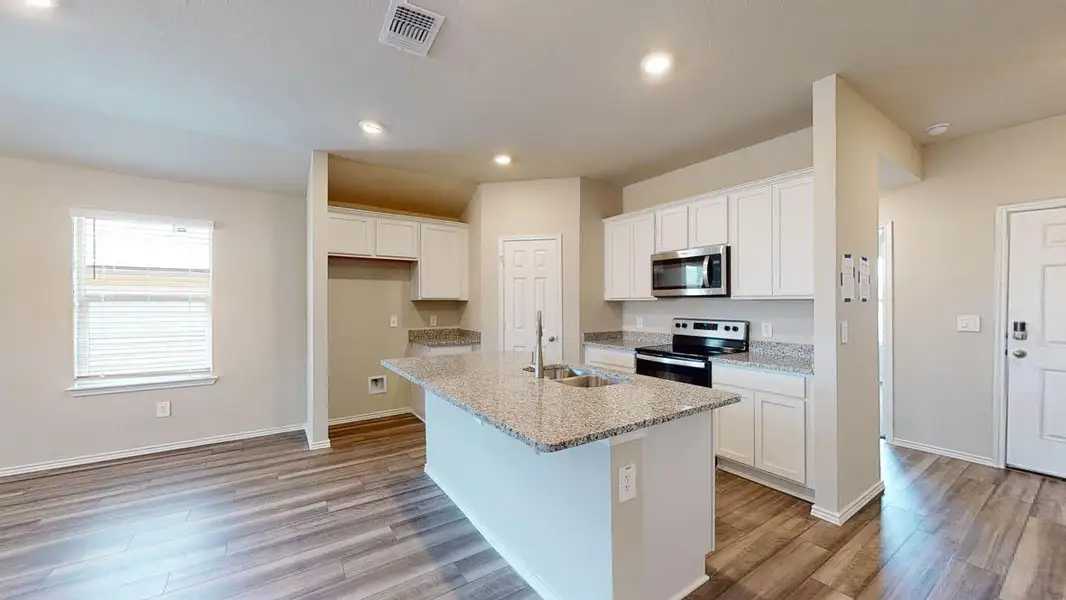 Kitchen with stainless steel appliances, white cabinetry, a center island with sink, light wood finished floors, and recessed lighting