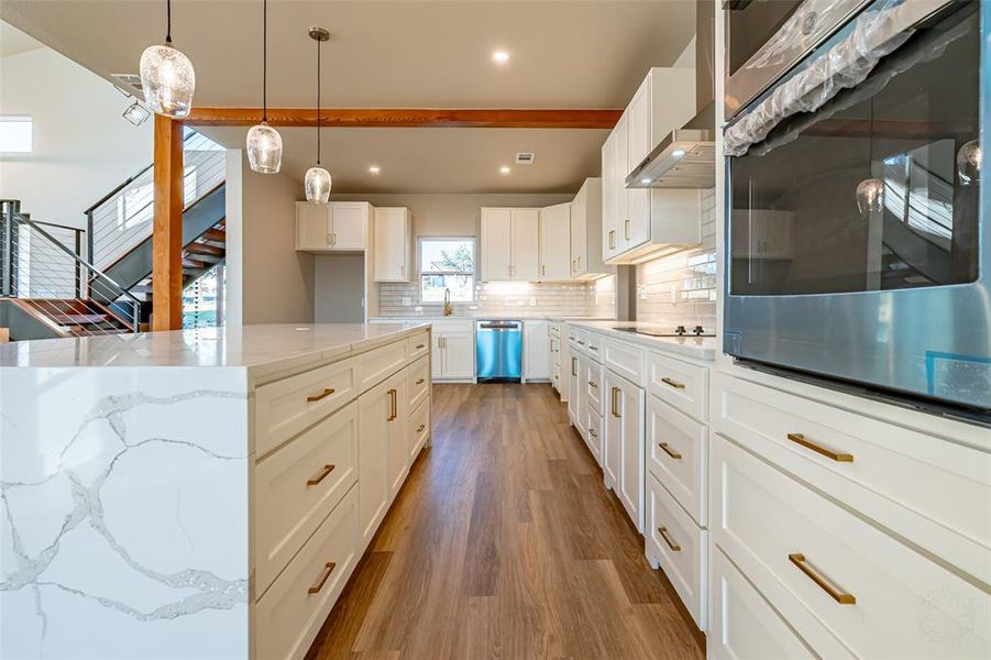 Kitchen featuring appliances with stainless steel finishes, backsplash, light stone countertops, white cabinets, and dark wood-type flooring Kitchen featuring appliances with stainless steel finishes, backsplash, light stone countertops, white cabinets, and dark wood-type flooring