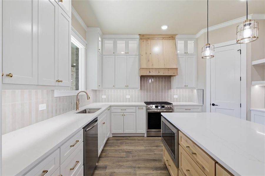 Modern kitchen featuring white cabinetry, light wood-finish flooring, a stainless steel range, and a kitchen island with built-in microwave