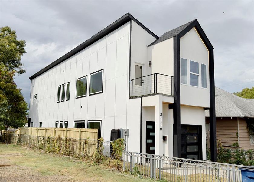 View of front of property with board and batten siding, a balcony, and stucco siding