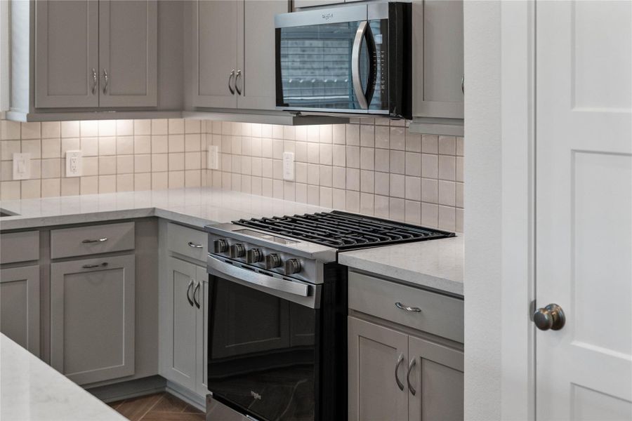 Showcased here is a Whirlpool gas range, paired with a steam microwave equipped with sensor cooking—all framed by an elegant tile backsplash. Showcased here is a Whirlpool gas range, paired with a steam microwave equipped with sensor cooking—all framed by an elegant tile backsplash.