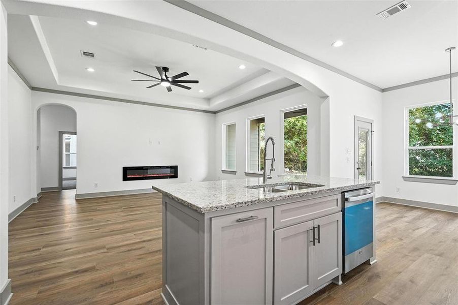 Kitchen with arched walkways, light stone countertops, a raised ceiling, dark wood-style floors, and recessed lighting Kitchen with arched walkways, light stone countertops, a raised ceiling, dark wood-style floors, and recessed lighting