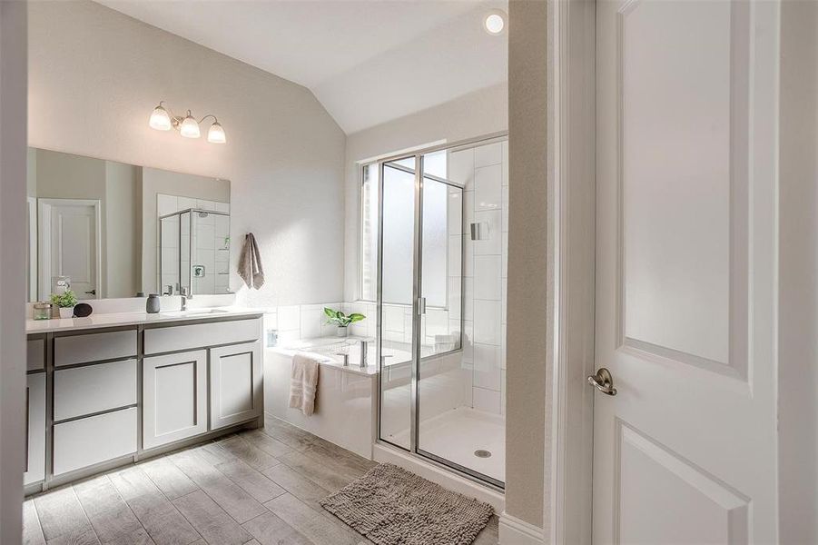 Primary bathroom with garden tub and walk-in shower with seating, dual sink vanity