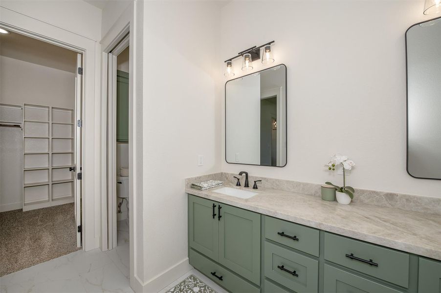 Full bath featuring light marble finish flooring, vanity, and a spacious closet