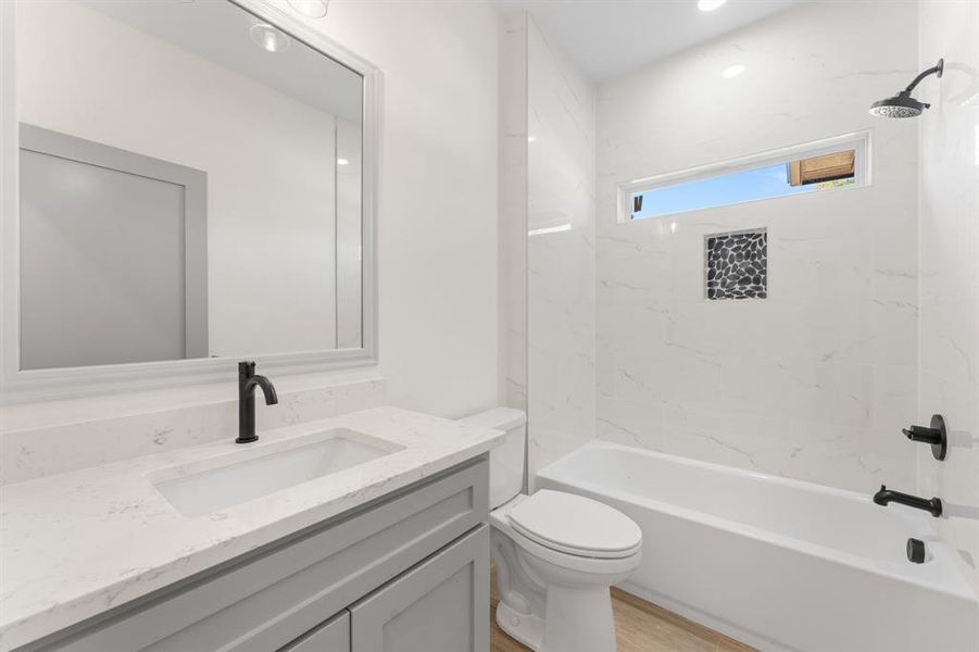 Full bath featuring  shower combination, vanity, and light wood-style floors