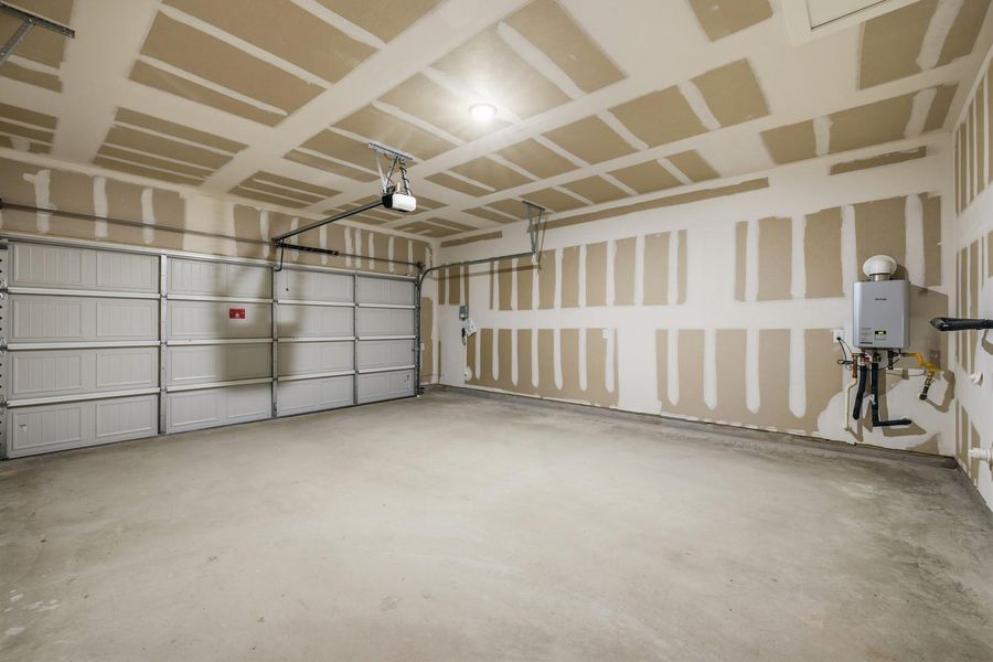 An immaculate garage offers a clean concrete floor and an automatic overhead door, ready for vehicles or storage.