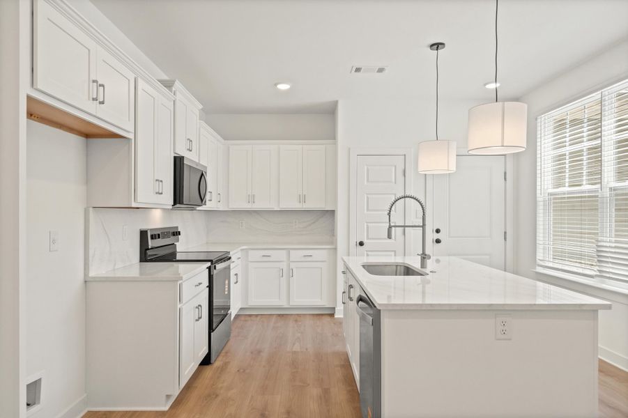 Contemporary kitchen featuring white cabinetry, light countertops, wood-finish flooring, a kitchen island with an undermount sink and gooseneck faucet, and stainless steel appliances