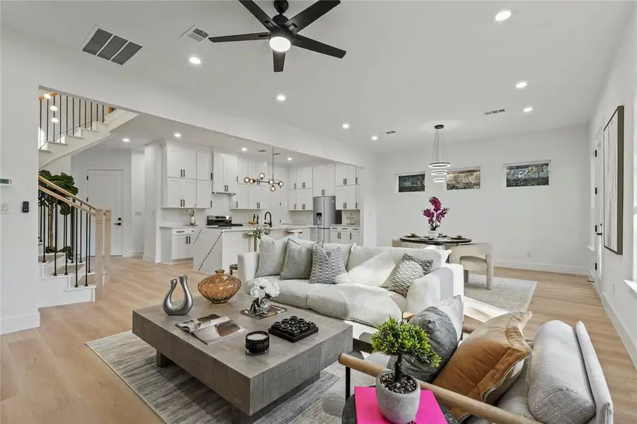 Living area with light wood-type flooring, recessed lighting, stairway, and ceiling fan