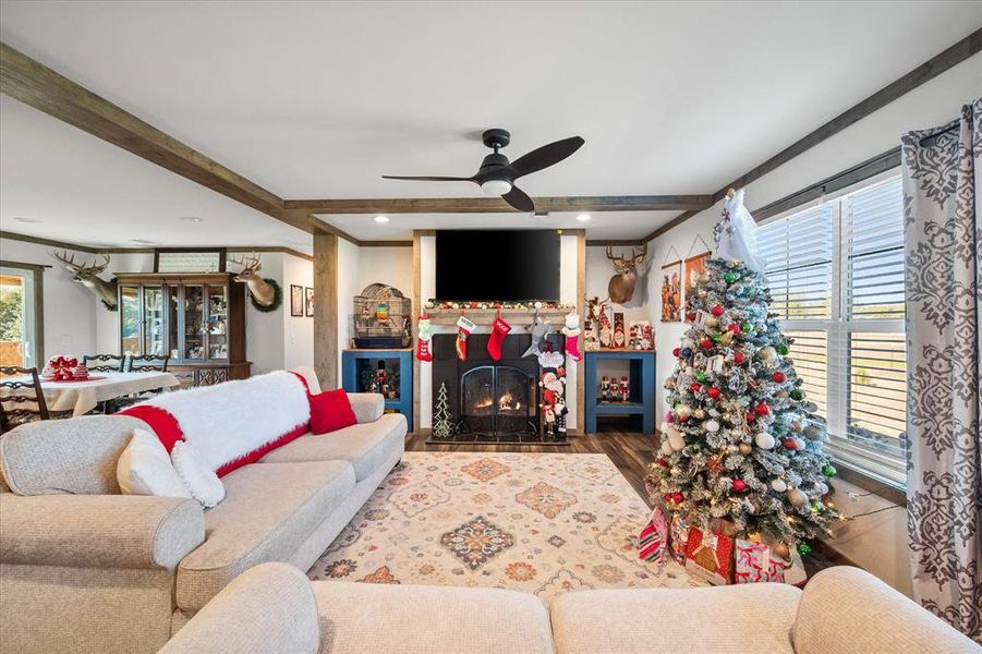 Living area with a fireplace with flush hearth, wood finished floors, ceiling fan, beam ceiling, and recessed lighting Living area with a fireplace with flush hearth, wood finished floors, ceiling fan, beam ceiling, and recessed lighting