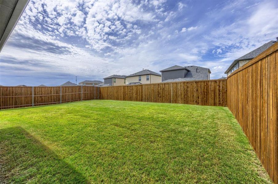 Private backyard featuring a level lawn and wood privacy fencing