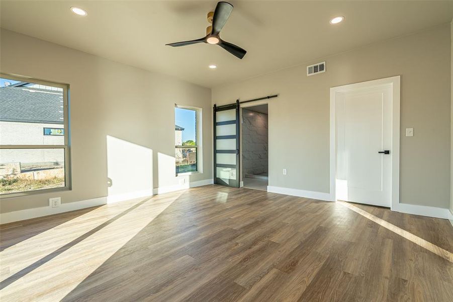 Unfurnished room featuring a barn door, recessed lighting, wood finished floors, and a ceiling fan Unfurnished room featuring a barn door, recessed lighting, wood finished floors, and a ceiling fan