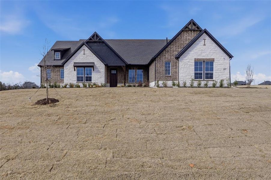 View of front of home with stone siding and a front lawn