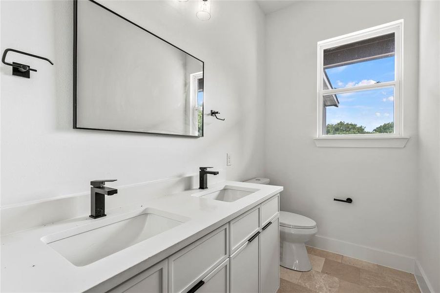 Bathroom featuring double vanity and stone finish floors