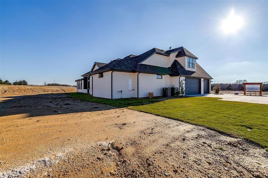 View of front of property featuring central air condition unit, a front yard, and a garage