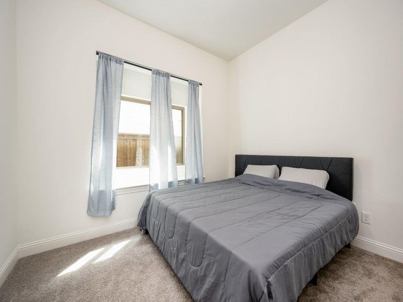 Bedroom featuring baseboards, lofted ceiling, and carpet flooring