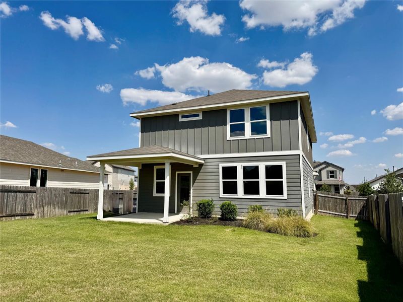 Rear view of property featuring a patio area, a fenced backyard, and board and batten siding