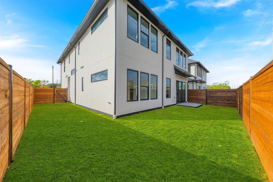 Rear view of house featuring a fenced backyard and stucco siding Rear view of house featuring a fenced backyard and stucco siding