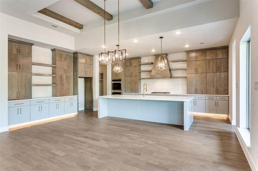Kitchen with open shelves, a large island, hanging light fixtures, light wood finished floors, and beam ceiling Kitchen with open shelves, a large island, hanging light fixtures, light wood finished floors, and beam ceiling