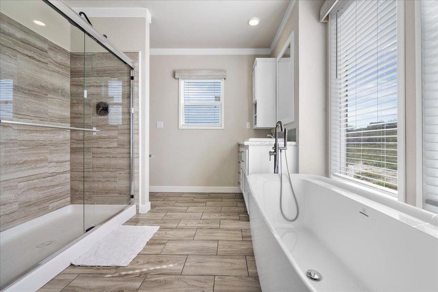 Full bath with vanity, a stall shower, a soaking tub, ornamental molding, and wood finish floors Full bath with vanity, a stall shower, a soaking tub, ornamental molding, and wood finish floors