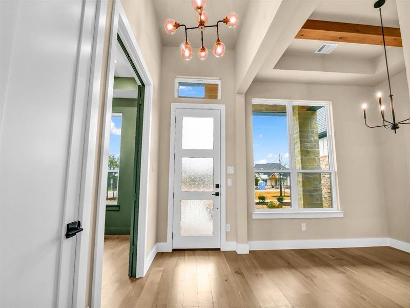 Foyer with beamed ceiling, light hardwood / wood-style floors, and a notable chandelier