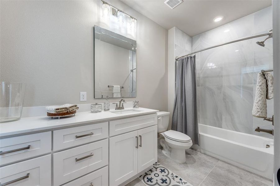 Bathroom featuring shower / bath combo with shower curtain, vanity, light tile patterned floors, and recessed lighting