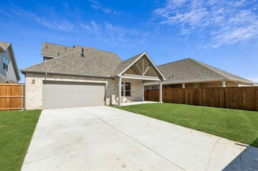 View of front facade featuring brick siding, a shingled roof, a patio area, and an attached garage View of front facade featuring brick siding, a shingled roof, a patio area, and an attached garage