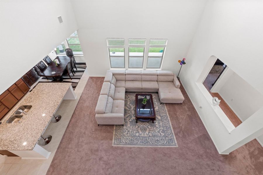 Two-story living area featuring a vaulted ceiling and three large windows