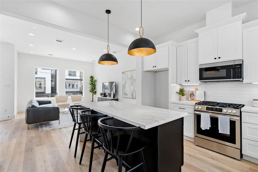 Stunning kitchen island pendants with sleek black accents elevate the second-floor space, where an oversized quartz waterfall island stands as a captivating centerpiece, blending style and functionality seamlessly.