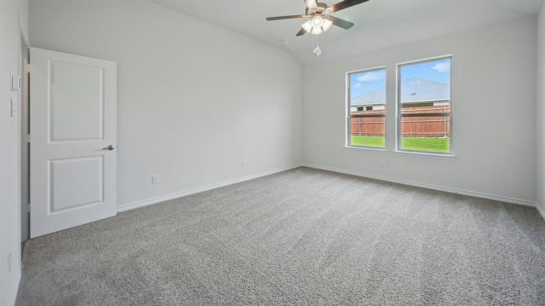 Empty room with lofted ceiling, carpet flooring, and a ceiling fan
