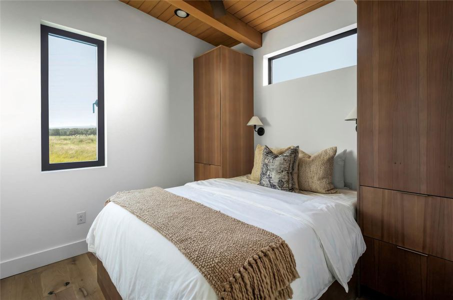 Cozy secondary bedroom with custom built-ins, oversized windows, and minimalist modern finishes.