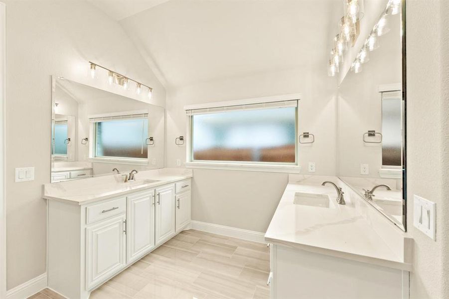 Bathroom with two vanities, vaulted ceiling, and wood finish floors