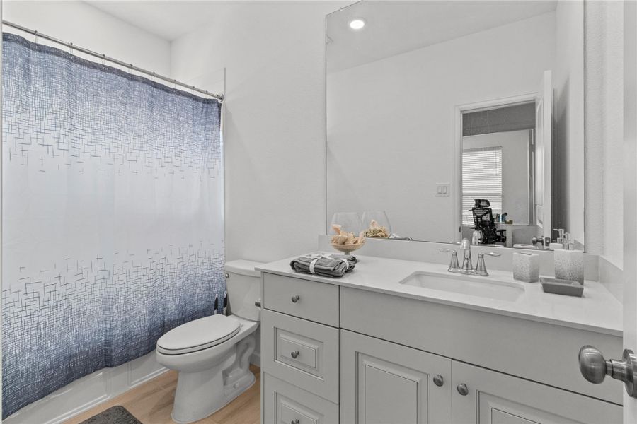 Bright and modern bathroom featuring a sleek vanity with ample storage, a large mirror, and a stylish shower curtain accentuating the space. Bright and modern bathroom featuring a sleek vanity with ample storage, a large mirror, and a stylish shower curtain accentuating the space.