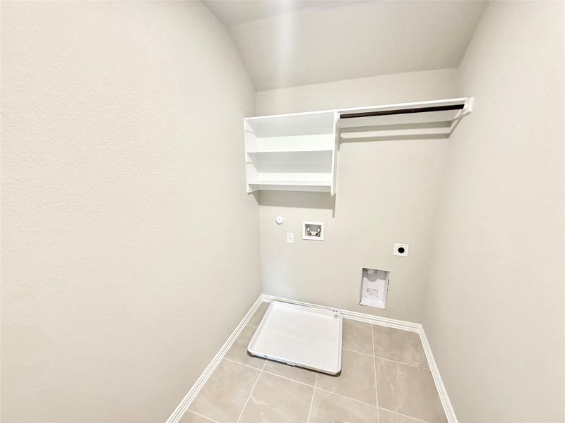 Laundry area featuring electric dryer hookup, hookup for a gas dryer, washer hookup, and tile patterned flooring Laundry area featuring electric dryer hookup, hookup for a gas dryer, washer hookup, and tile patterned flooring