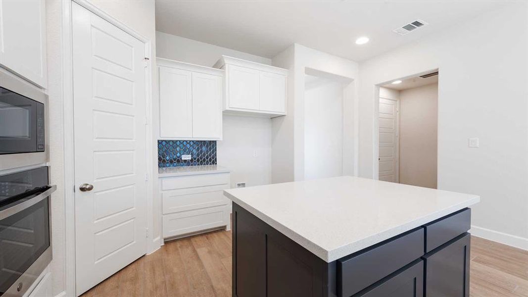 Kitchen featuring white cabinetry, a center island, stainless steel appliances, backsplash, and light hardwood / wood-style floors