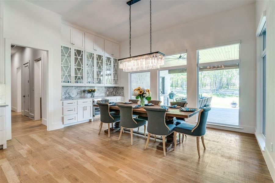 Dining room featuring a chandelier, light hardwood / wood-style floors, and a towering ceiling