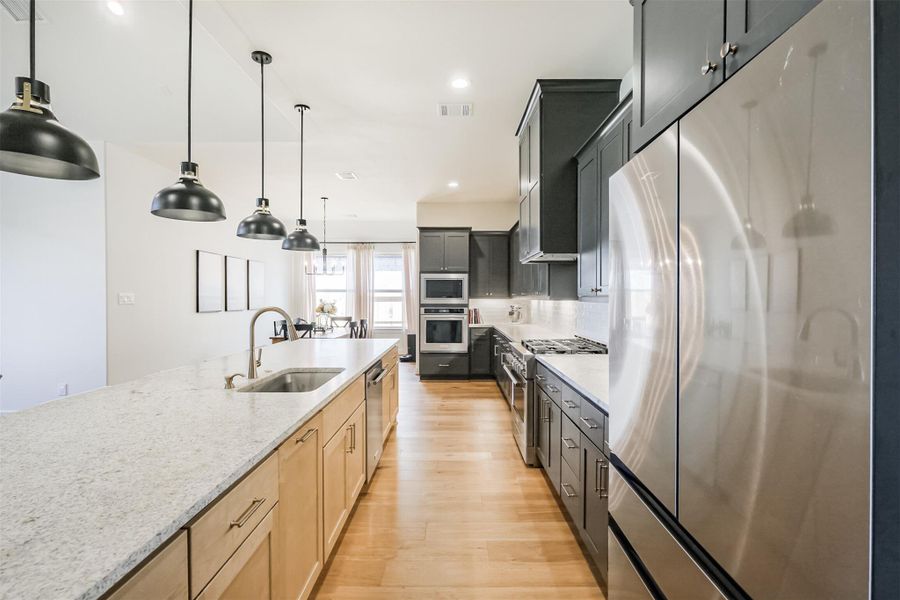 Expansive island and spacious kitchen offering an upgraded kitchen faucet, second oven, and built in microwave.