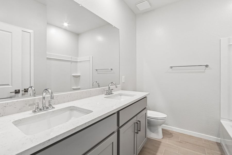 A bathroom with a sink toilet and mirror.