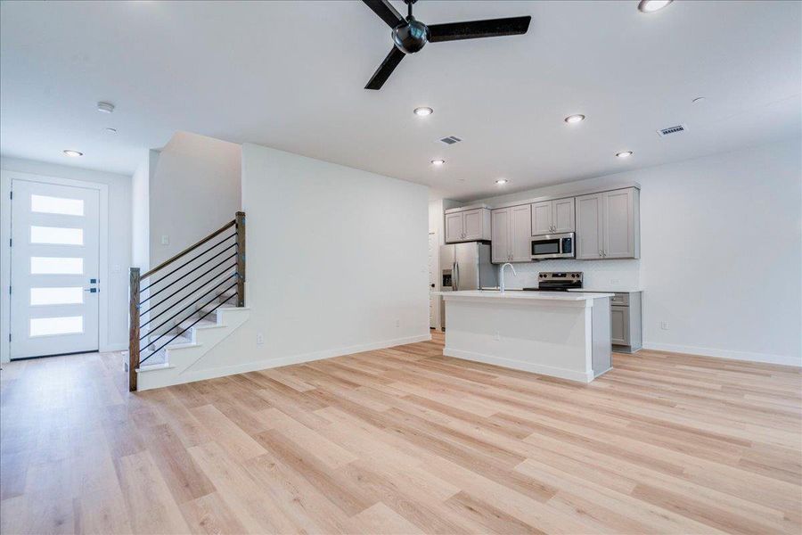 An open floorplan living area flows seamlessly into a modern kitchen with island seating.