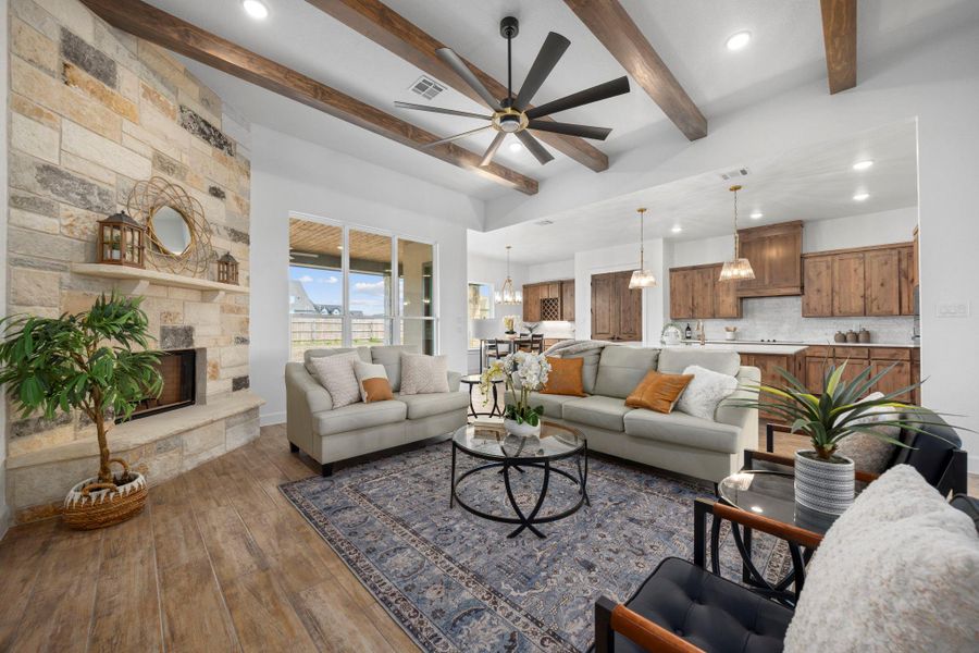 Living area with ceiling fan, a fireplace, dark wood-type flooring, beamed ceiling, and a chandelier