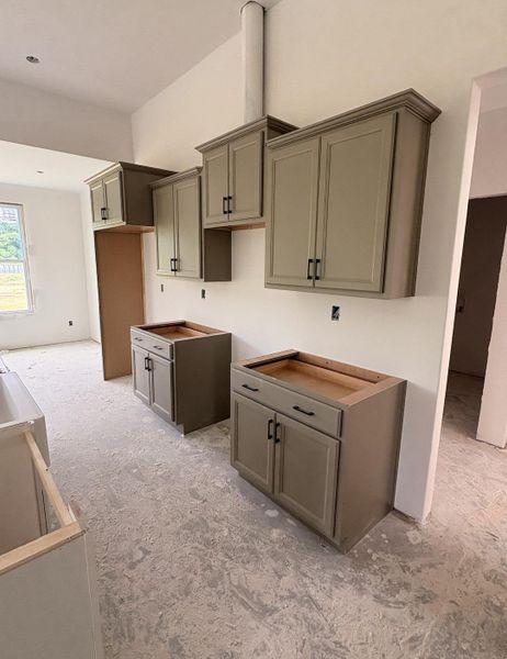 Kitchen featuring installed cabinetry with crown molding, black hardware, and shaker-style doors Kitchen featuring installed cabinetry with crown molding, black hardware, and shaker-style doors