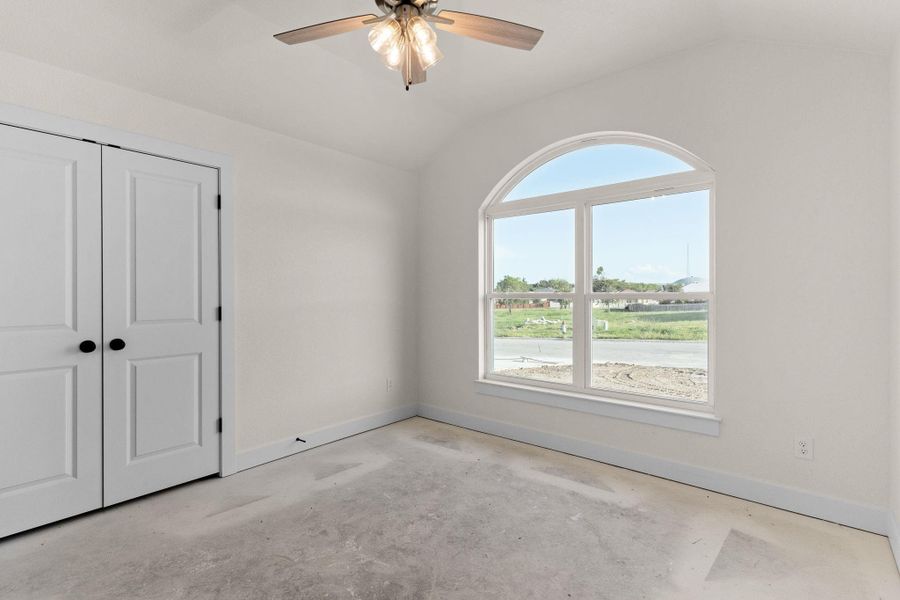 Unfurnished bedroom featuring vaulted ceiling, unfinished concrete flooring, a closet, and a ceiling fan Unfurnished bedroom featuring vaulted ceiling, unfinished concrete flooring, a closet, and a ceiling fan