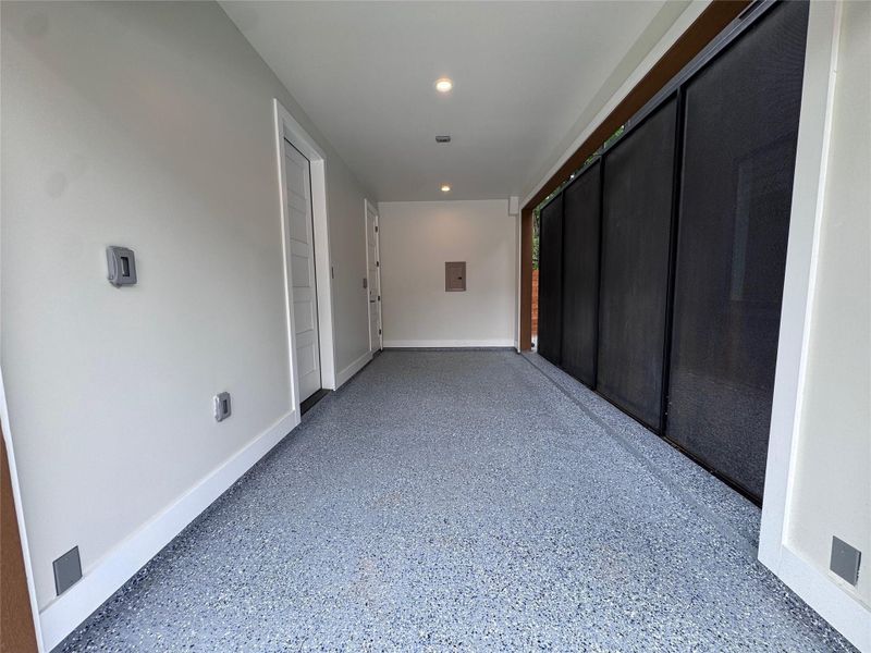 Garage space featuring an epoxy-coated floor, recessed lighting, and a roll-down mesh screen