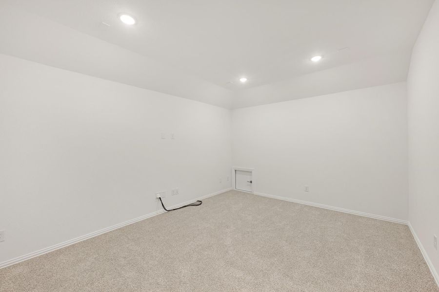 Empty room with white walls, beige carpet, recessed lighting, and a small access panel on the wall