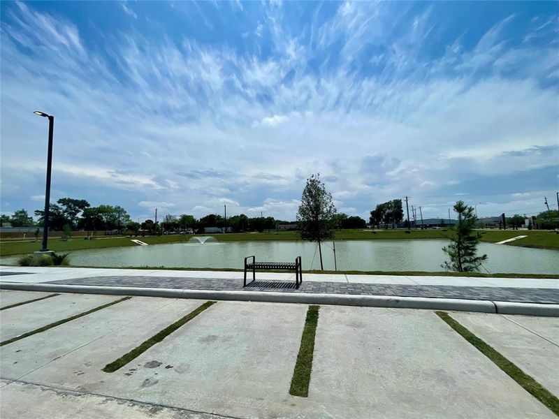 Lovely paved walking track surrounding a serene pond with water feature and benches scattered throughout located in the gated community of Alicante.