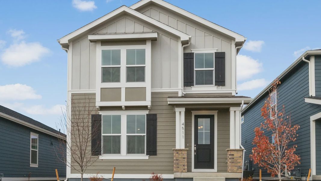 Timnath Lakes gem featuring striking gray siding, elegant black shutters, and expansive windows, exuding refined sophistication.